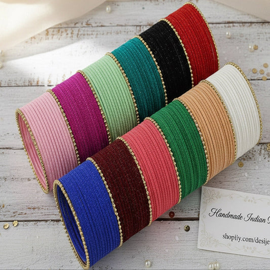 Colorful bangles on a wooden surface with a card displaying a website URL.