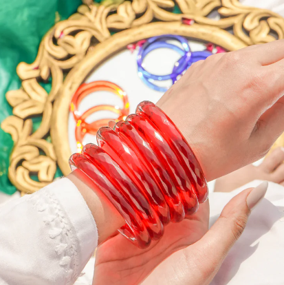 Hand wearing a red bracelet with a decorative background